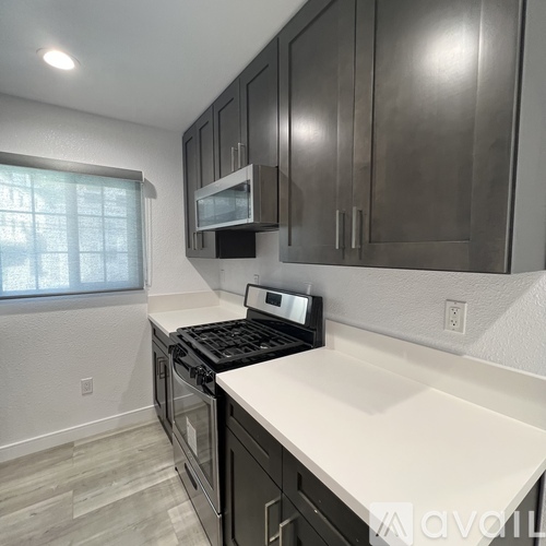 A kitchen with dark cabinets and a white countertop.