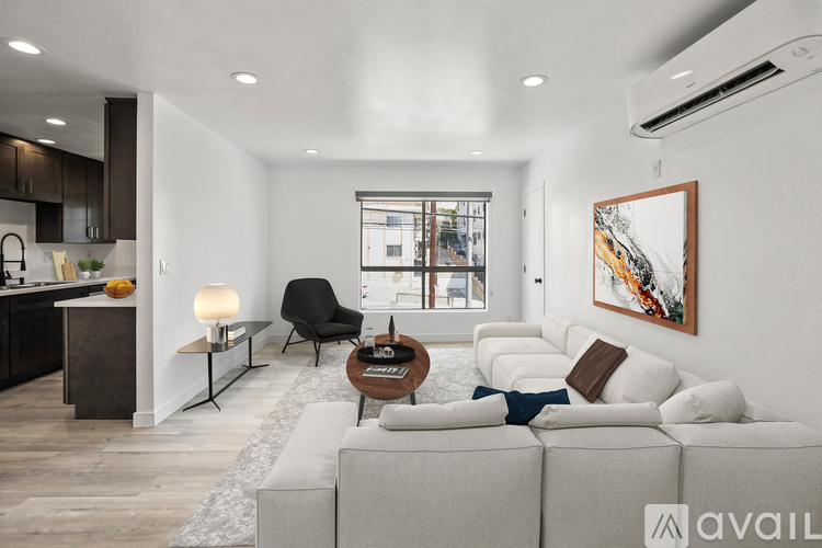 A modern living room with a large couch, a coffee table, and a painting on the wall.