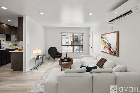A modern living room with a large couch, a coffee table, and a painting on the wall.
