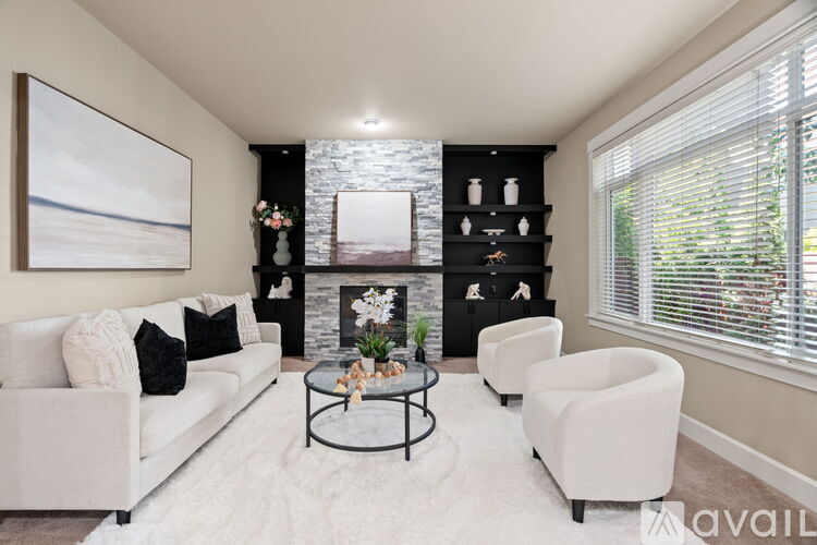 A living room with a white couch, a coffee table, and a fireplace with a painting above it.