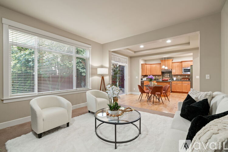 A living room with a white sofa, a coffee table, and a dining table.