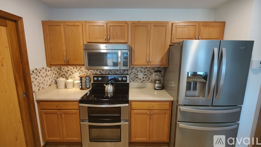 A kitchen with wooden cabinets and a stainless steel refrigerator.