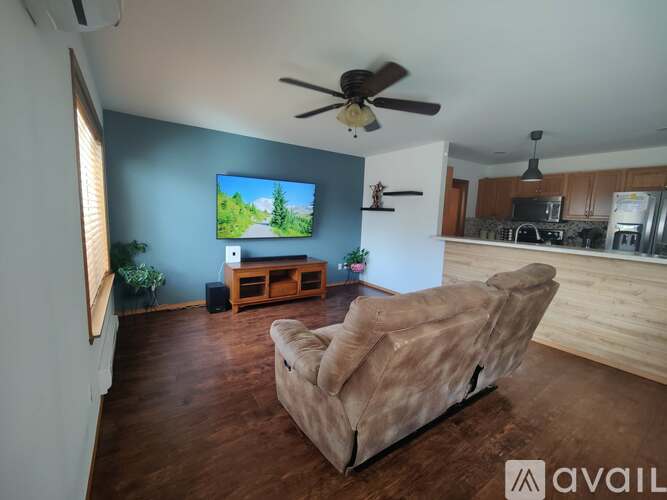 A living room with a beige couch and a flat screen TV mounted on the wall.