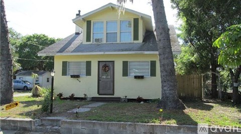 A yellow house with a black door and a wreath on the door.