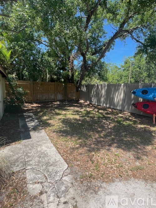 A backyard with a wooden fence and a blue kayak.