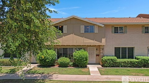 A beige house with a brown roof and a white door.