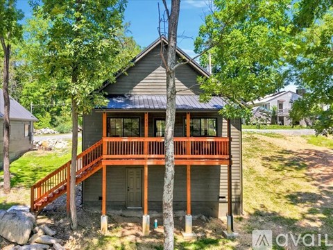 A small house with a porch surrounded by trees.