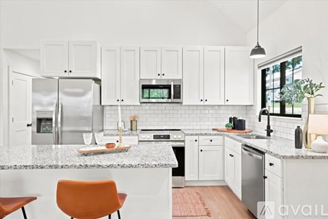 A kitchen with white cabinets and a marble countertop.