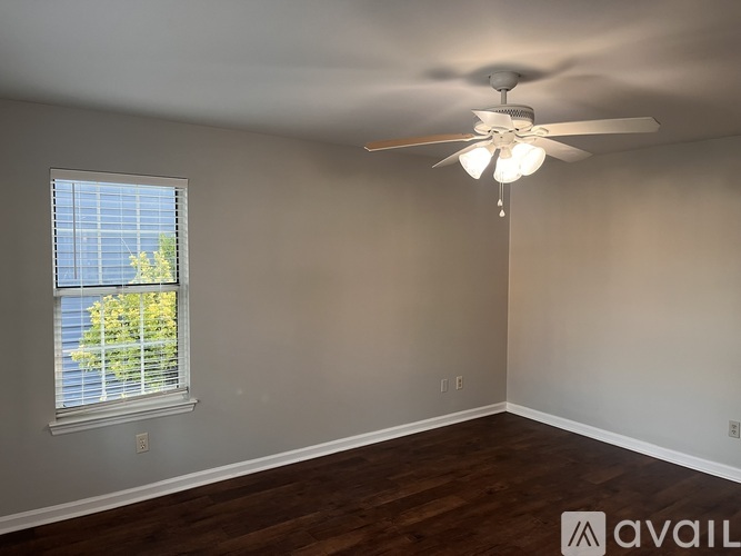 A room with a ceiling fan and a window with blinds.