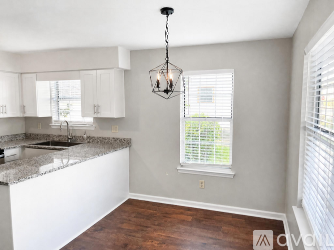 A kitchen with a granite countertop and a chandelier hanging from the ceiling.