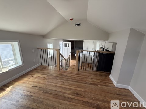 A spacious room with wooden flooring and a staircase leading to another level.