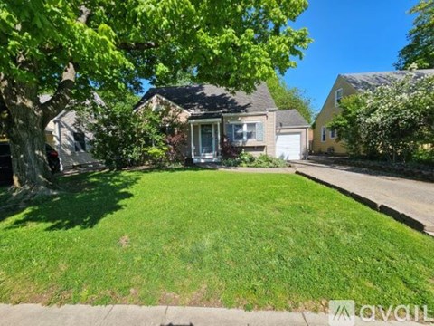 A house with a green lawn and trees in front of it.