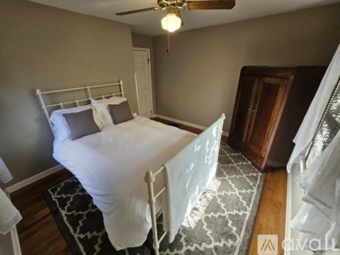 A bedroom with a white bed and a ceiling fan.