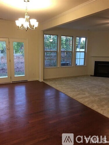 A living room with a chandelier, a fireplace, and a sliding glass door.