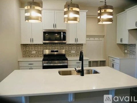 A kitchen with a white countertop and a black faucet.