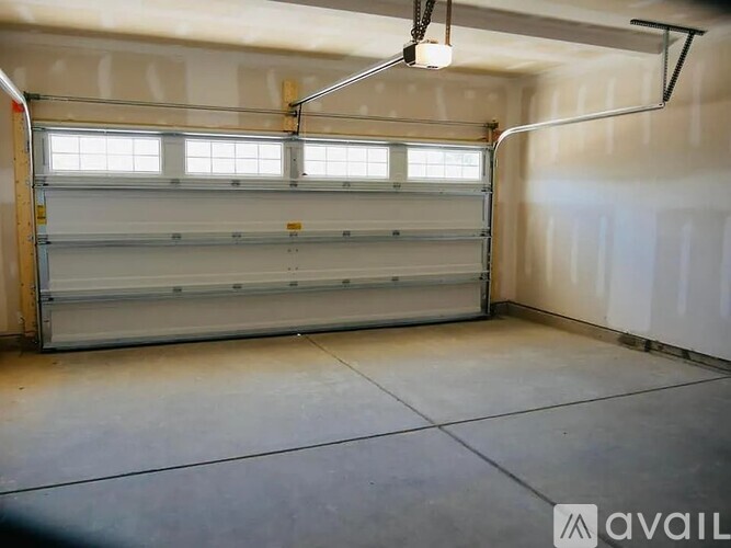 A spacious garage with a closed white door and a light hanging from the ceiling.
