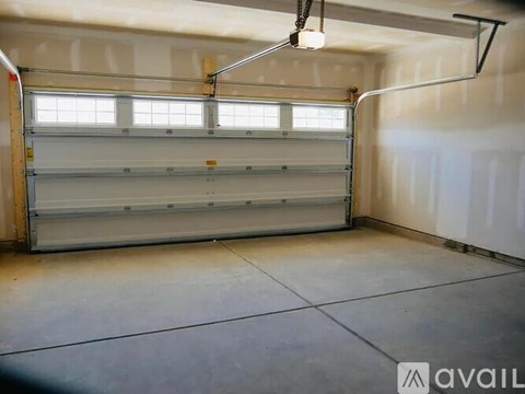A spacious garage with a closed white door and a light hanging from the ceiling.