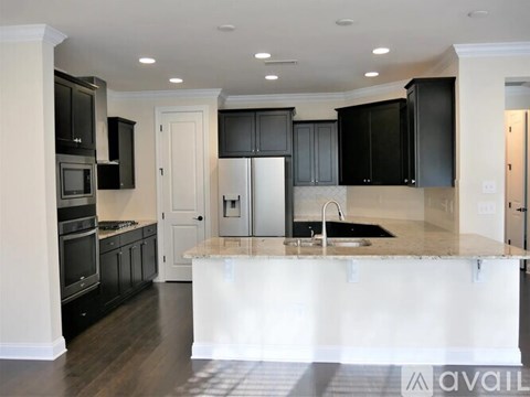 A kitchen with black cabinets and a white island.