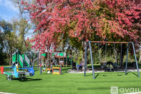 A playground with a swing set and a tree with pink leaves.