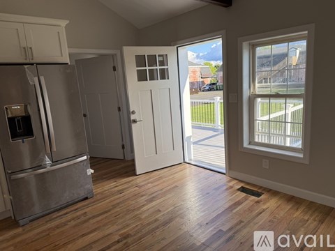 A kitchen with a refrigerator, cabinets, and a door leading to a balcony.