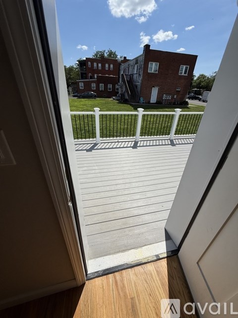 A view from inside a room looking out to a wooden deck and a brick building.