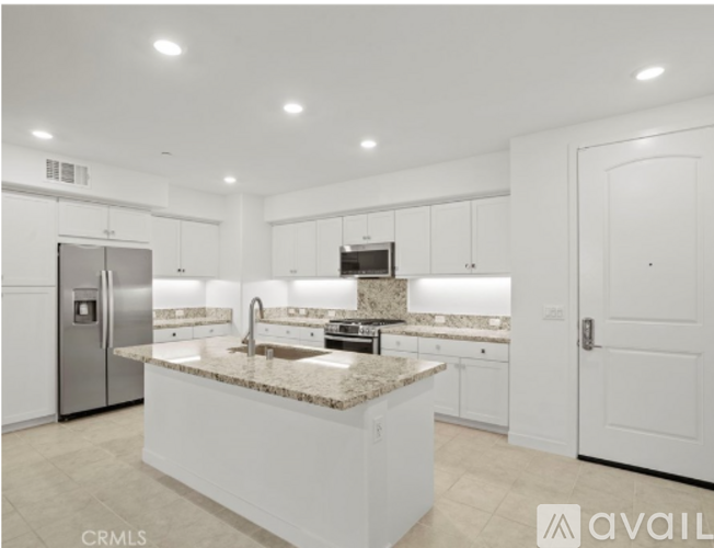 A modern kitchen with white cabinets and a granite countertop.