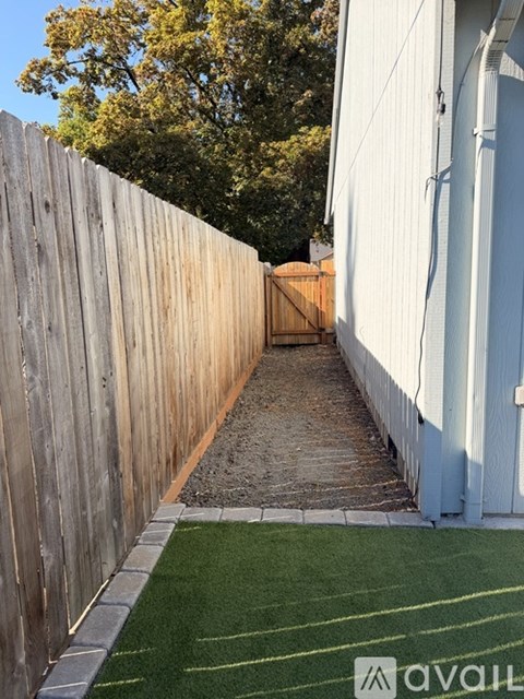 A narrow alley with a wooden fence on one side and a white building on the other.