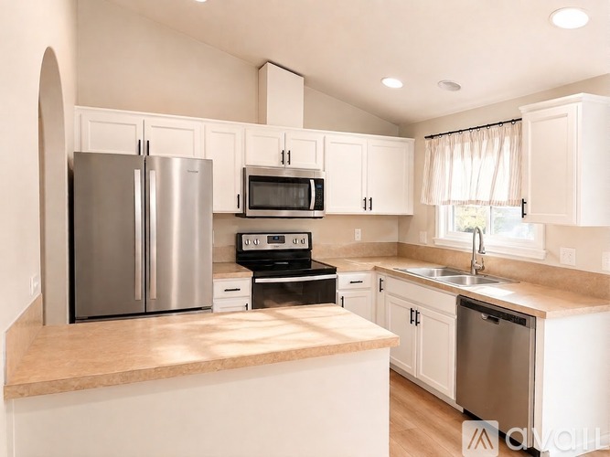 A kitchen with white cabinets and a stainless steel refrigerator.