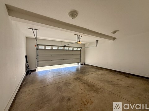 A spacious garage with a closed white door and a light brown floor.
