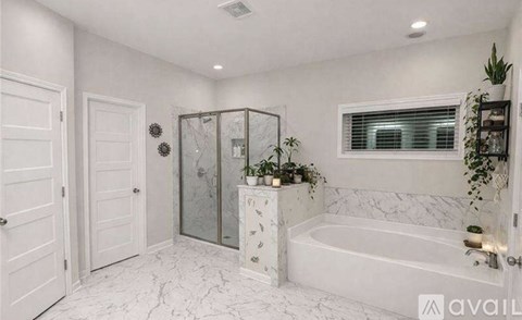 A white bathroom with a marble floor and a glass shower enclosure.