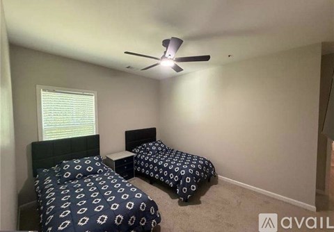 A bedroom with two beds and a ceiling fan.