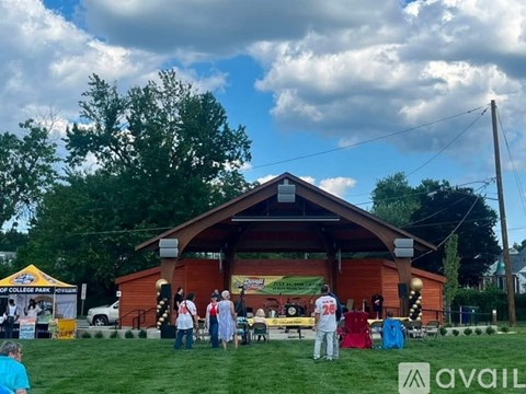 A group of people are gathered outside a wooden building with a tent set up in front.