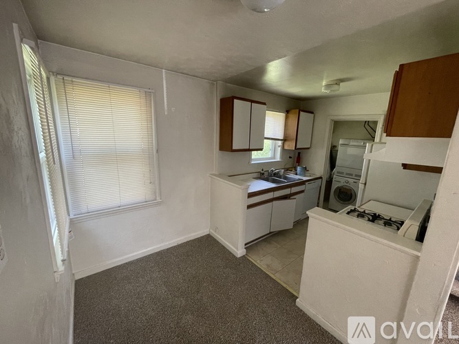 A small, white kitchen with a window and a washing machine.