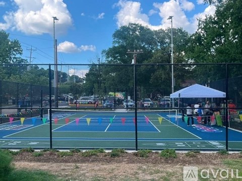 A tennis court with a blue canopy tent and people playing tennis.