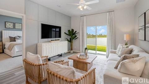 A living room with a white sofa, a wooden coffee table, and a flat-screen TV mounted on the wall.