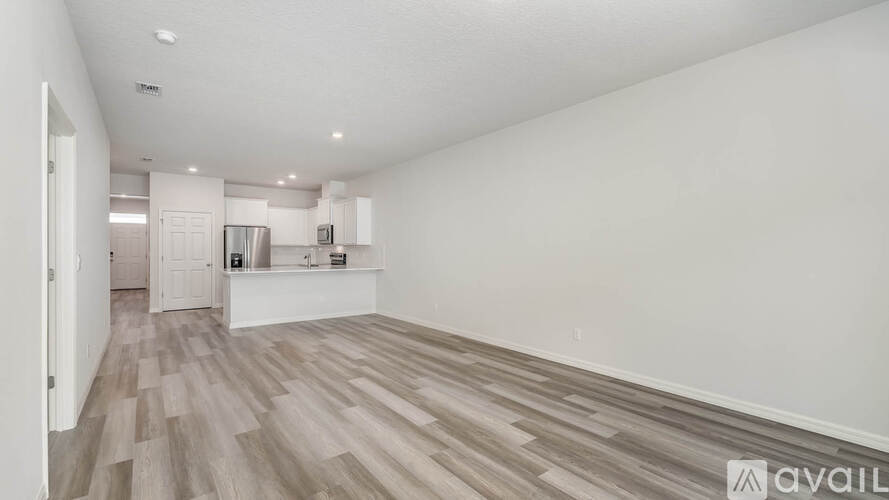 A spacious room with wooden flooring and white walls.