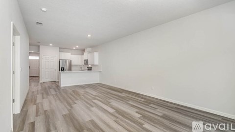 A spacious room with wooden flooring and white walls.