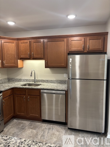 A kitchen with wooden cabinets and a stainless steel refrigerator.