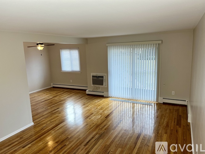 A room with wooden floors and a window with blinds.