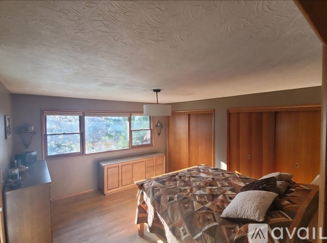 A bedroom with a bed, dresser, and window.