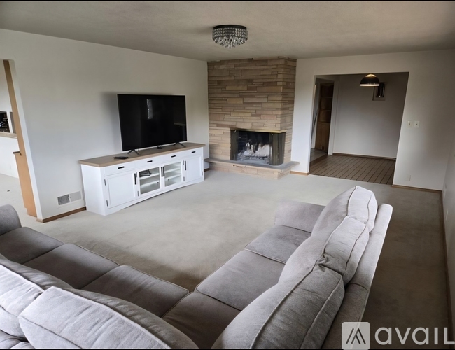 A living room with a grey sofa and a fireplace.