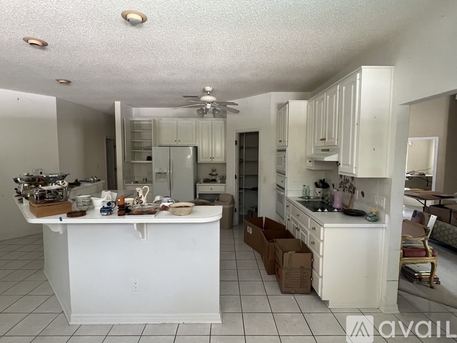 A kitchen with white cabinets and a white island with a counter top.