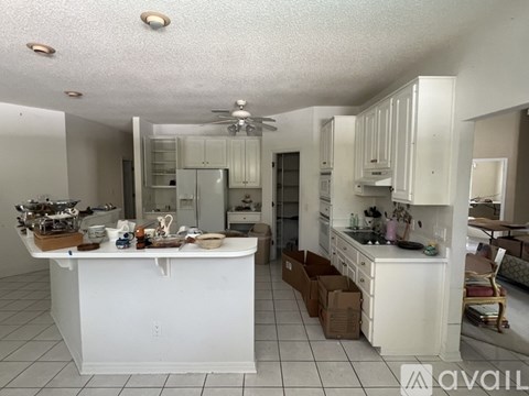 A kitchen with white cabinets and a white island with a counter top.