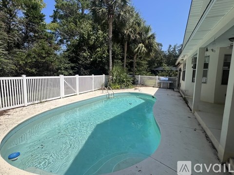 A small residential pool surrounded by a white fence.
