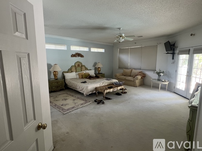 A bedroom with a bed, a couch, and a ceiling fan.