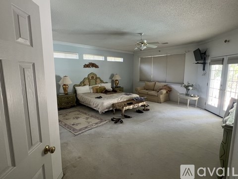 A bedroom with a bed, a couch, and a ceiling fan.
