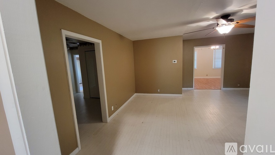 A room with a ceiling fan and light, and a door leading to another room.
