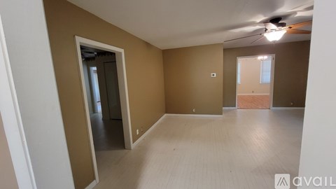 A room with a ceiling fan and light, and a door leading to another room.