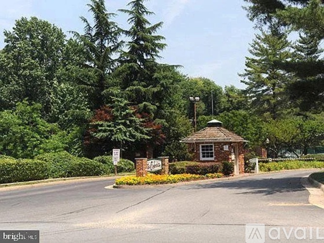 A small building with a sign in front of a tree.