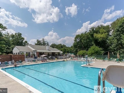 A large swimming pool surrounded by trees and a building in the background.